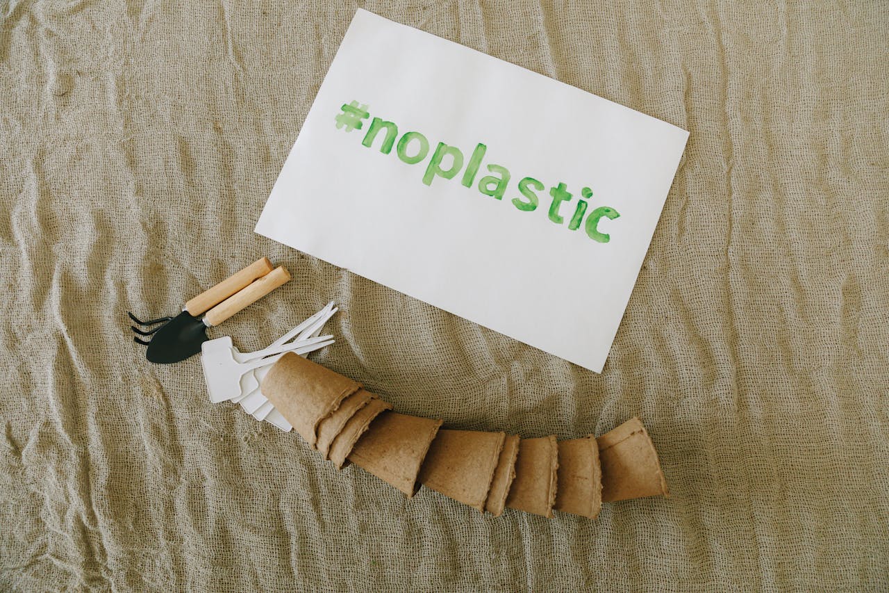 Top view of sustainable gardening tools on fabric with #noplastic sign.