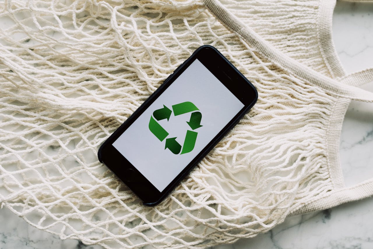 From above view of smartphone with recycling symbol on screen on white mesh bag on marble table in light room